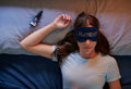 a woman laying on a bed wearing a sleep mask