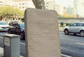 A mattress leans against a tree on the sidewalk.