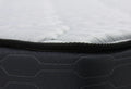 Close-up of a dark gray mattress with white bedding.