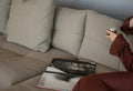 Person relaxing on a sofa with a drink and book